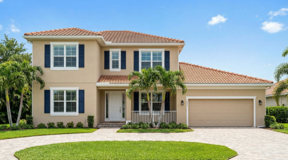 Two-story Florida stucco home freshly painted in warm beige with navy shutters - JPL Painting exterior painting
